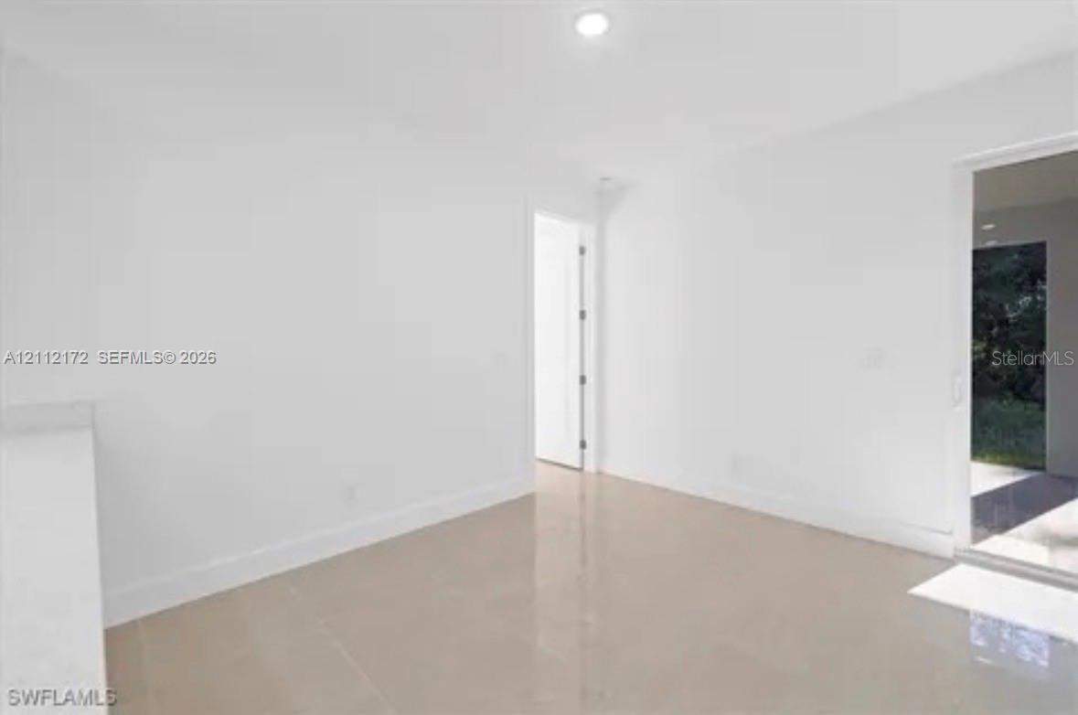 Neutral interior featuring light-toned tile flooring, recessed ceiling lighting, and glass sliding doors