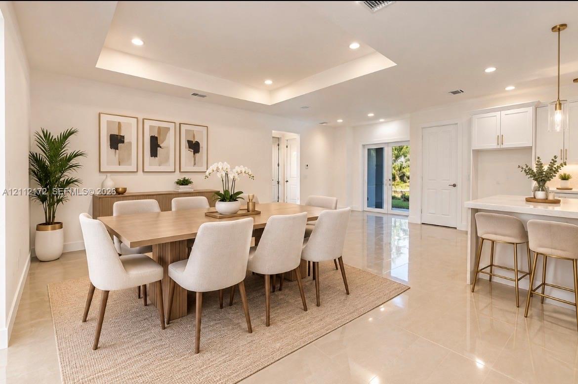 Tray ceiling with recessed lighting, large-format tile flooring, white shaker-style cabinetry, and pendant lighting