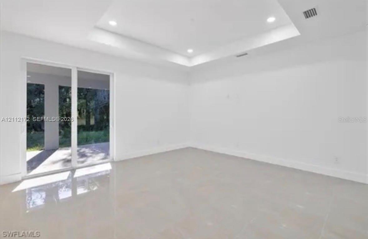 Interior space featuring a recessed tray ceiling, recessed lighting, polished tile flooring, and sliding glass doors Interior space featuring a recessed tray ceiling, recessed lighting, polished tile flooring, and sliding glass doors