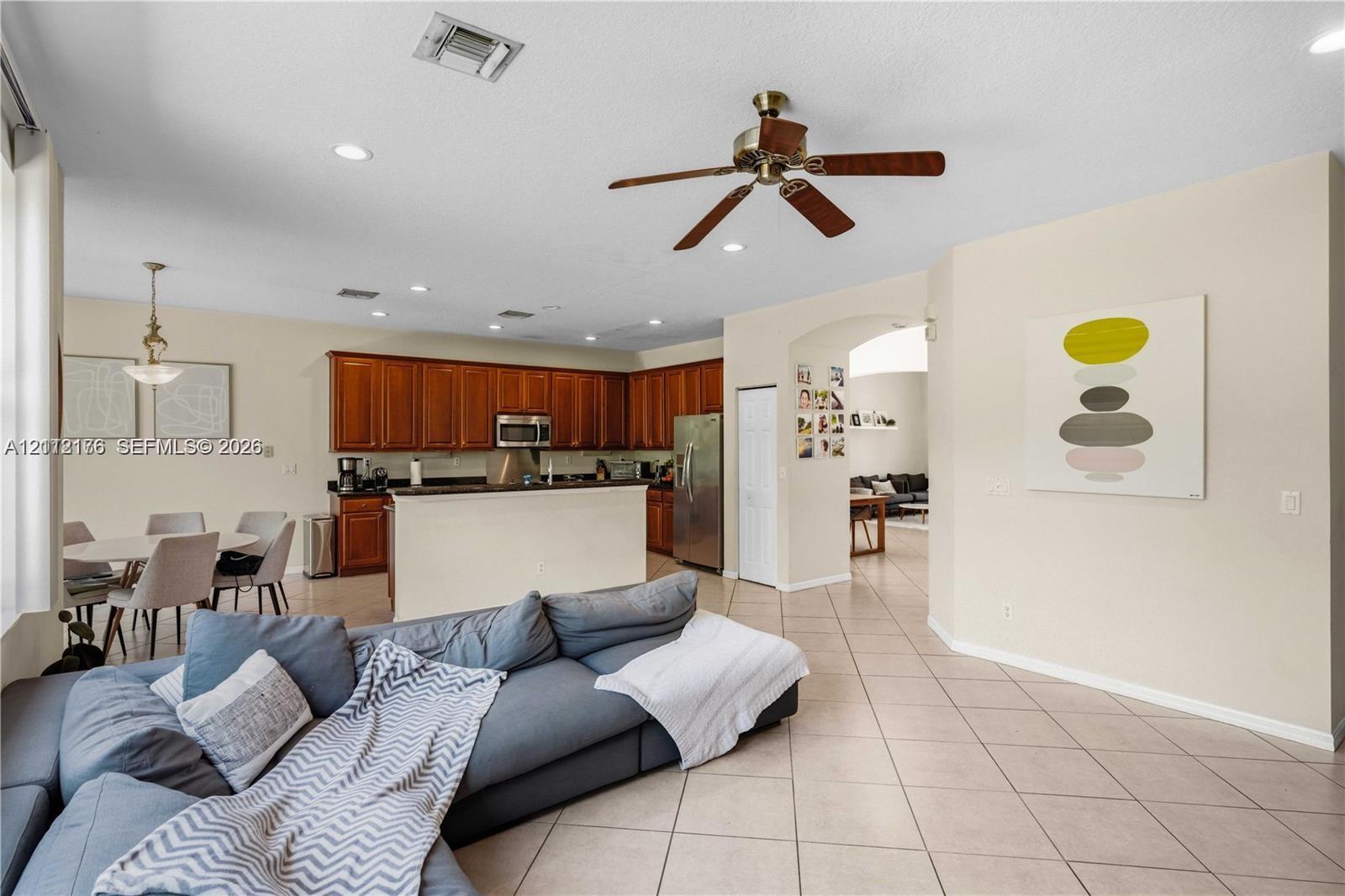 Open-concept kitchen featuring dark wood cabinetry, a breakfast bar, recessed lighting, a ceiling fan, and tile flooring