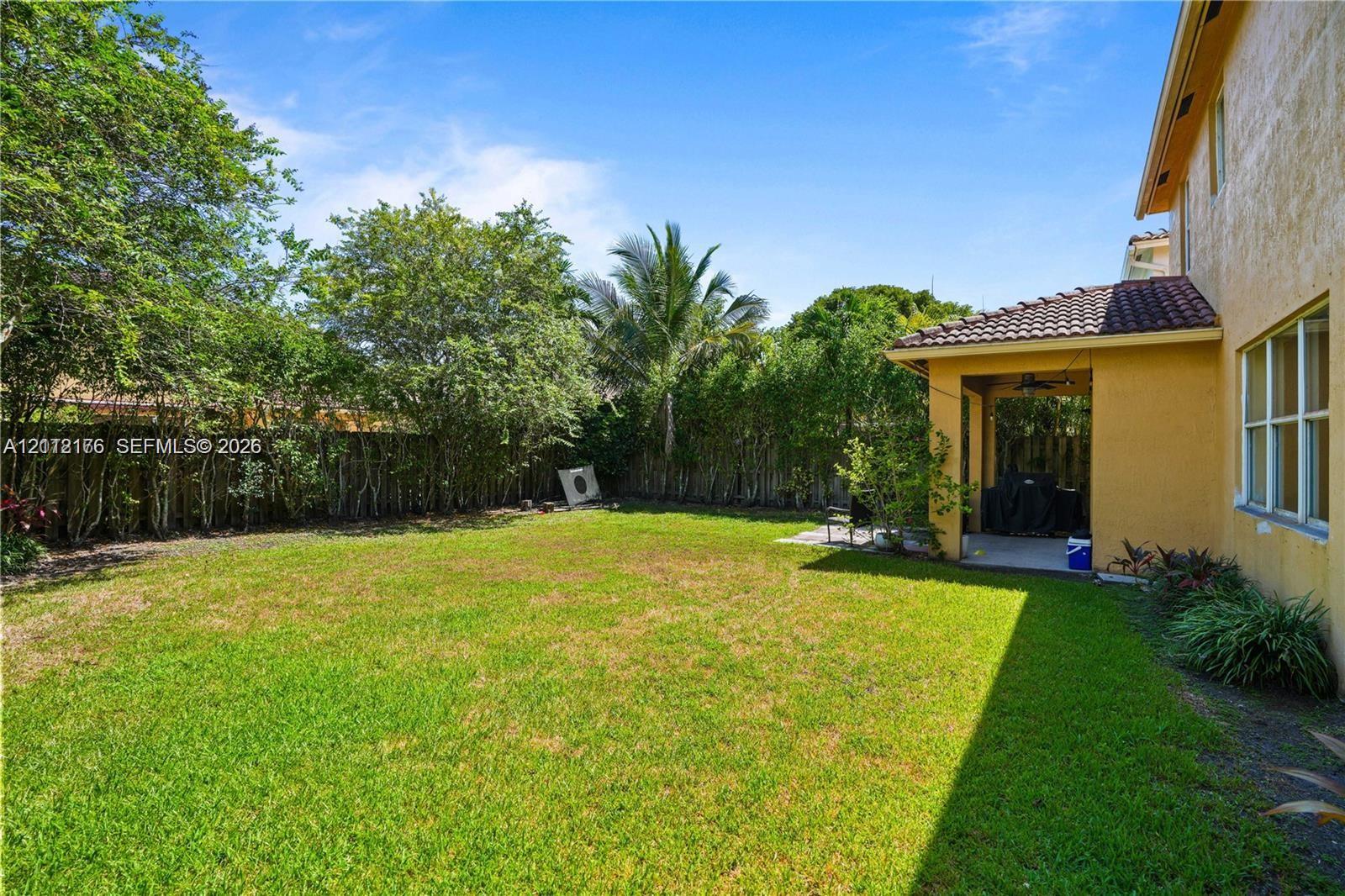 Backyard featuring a covered patio, tile roof, and perimeter greenery