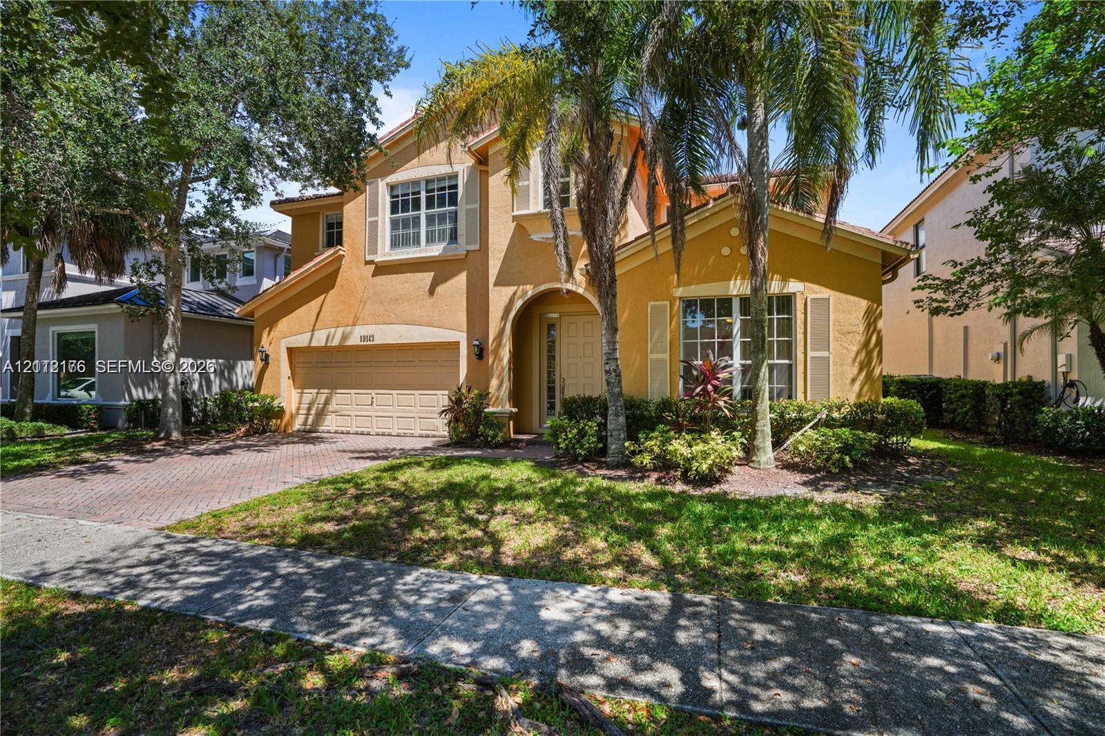 Stucco exterior featuring an arched entryway, shuttered windows, a two-car garage, and a brick-paver driveway Stucco exterior featuring an arched entryway, shuttered windows, a two-car garage, and a brick-paver driveway