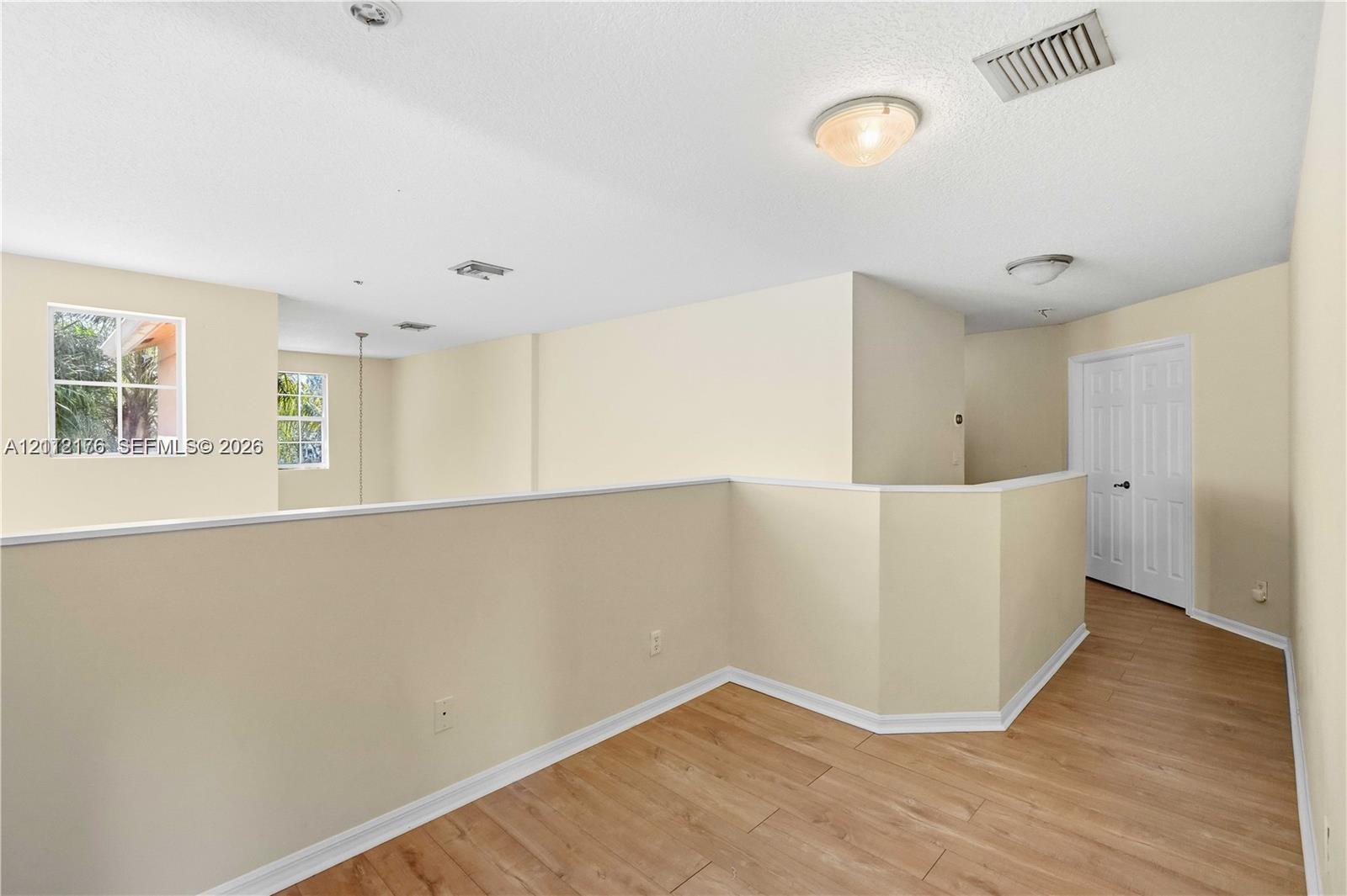 Open-concept mezzanine area featuring wood-finish flooring, recessed lighting, and white paneled doors Open-concept mezzanine area featuring wood-finish flooring, recessed lighting, and white paneled doors