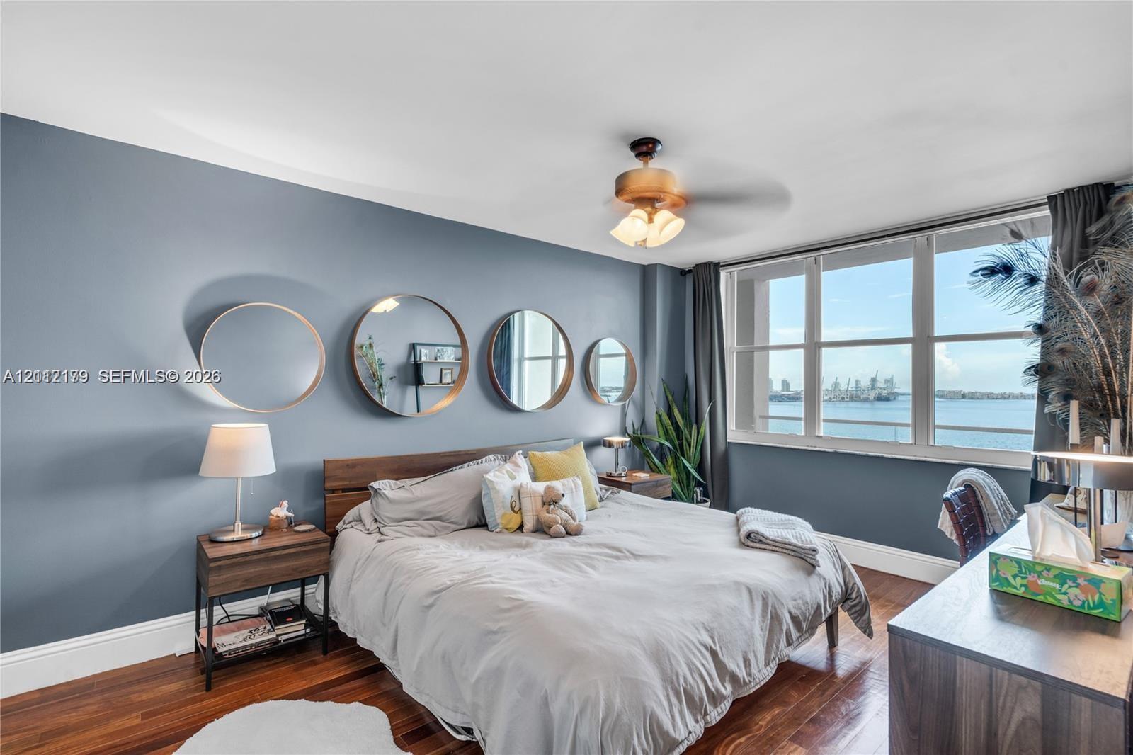 Room featuring wood-finish flooring, large floor-to-ceiling windows, and a ceiling-mounted light fixture with a fan