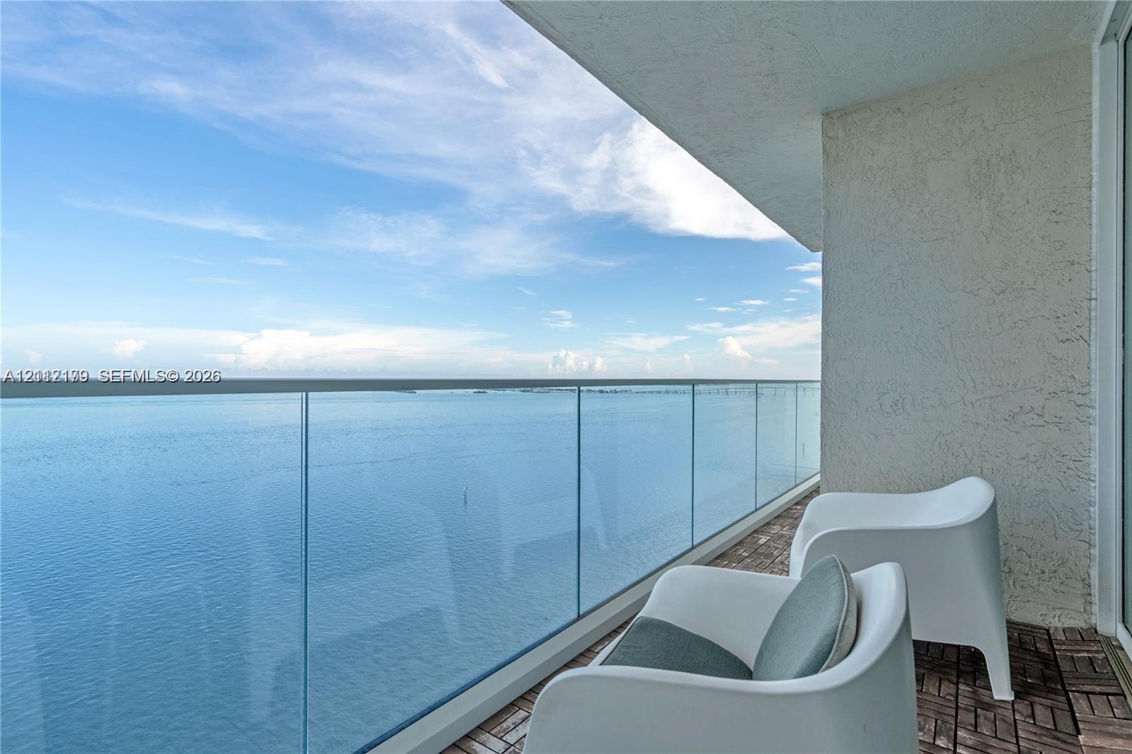 Private balcony featuring a glass panel railing, textured wall finish, and wood-finish modular tile flooring