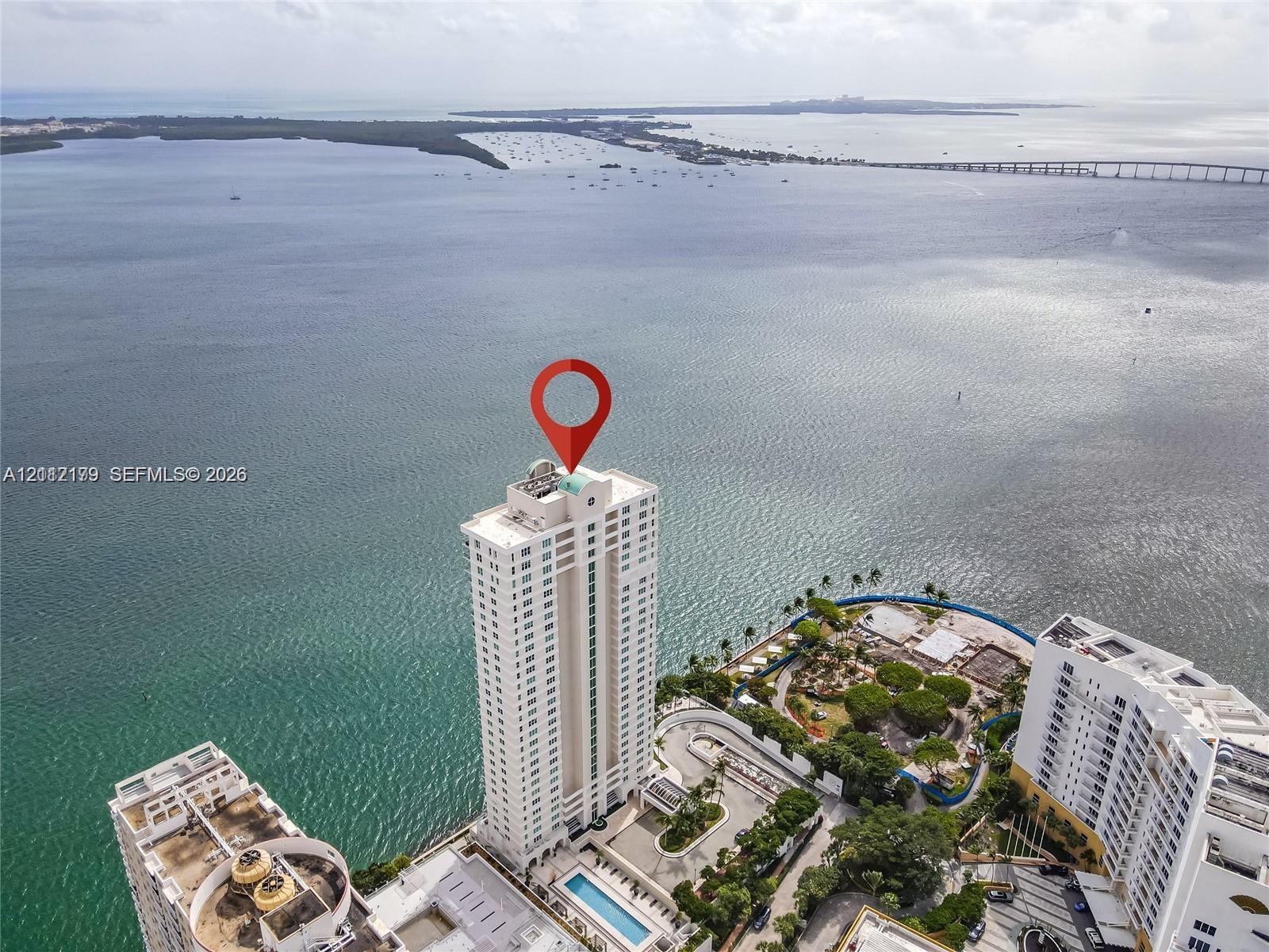 High-rise residential tower featuring a waterfront location, a rectangular swimming pool, and proximity to a causeway