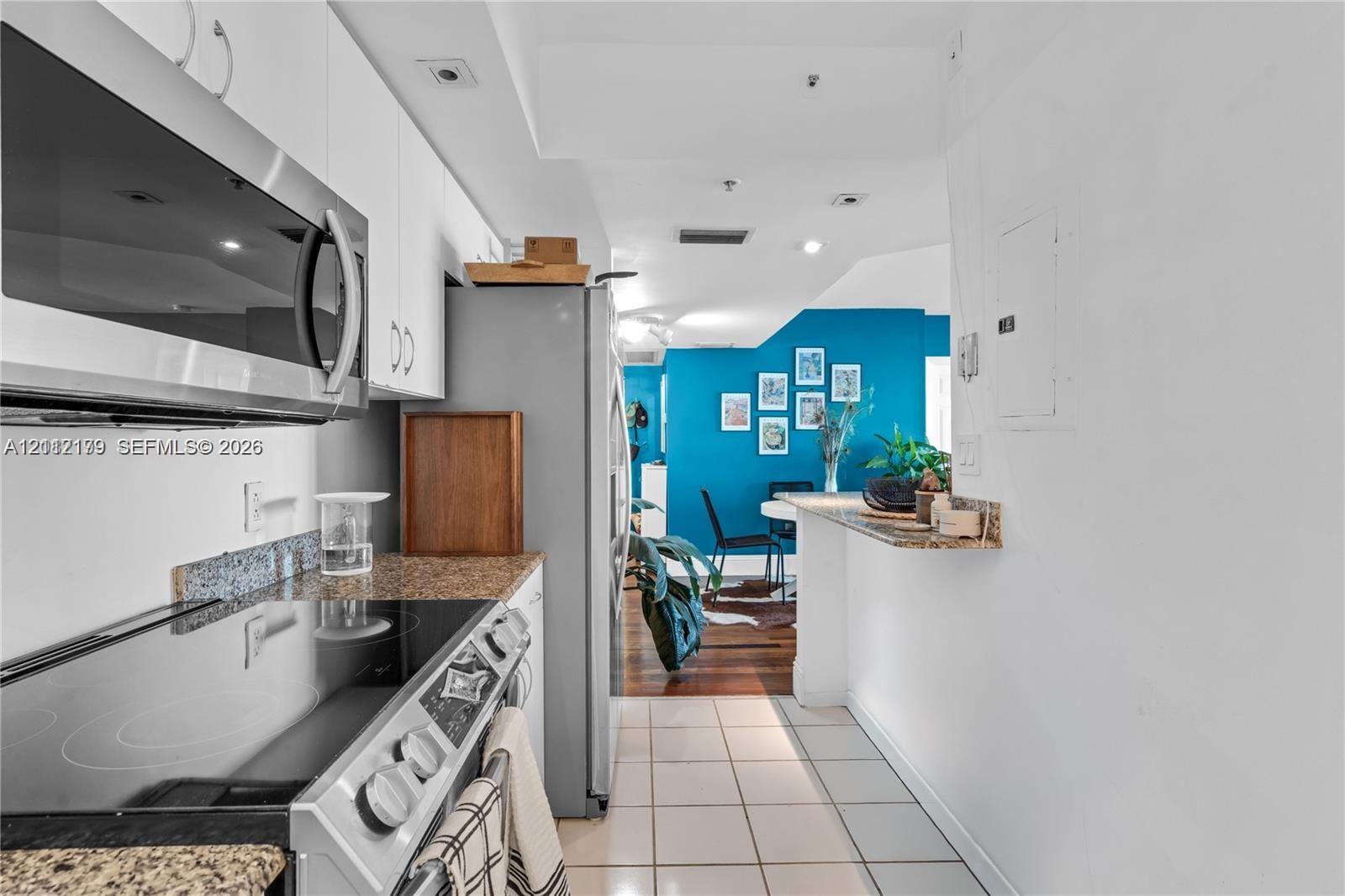 Kitchen featuring white cabinetry, stone-finish countertops, stainless steel appliances, and a breakfast bar