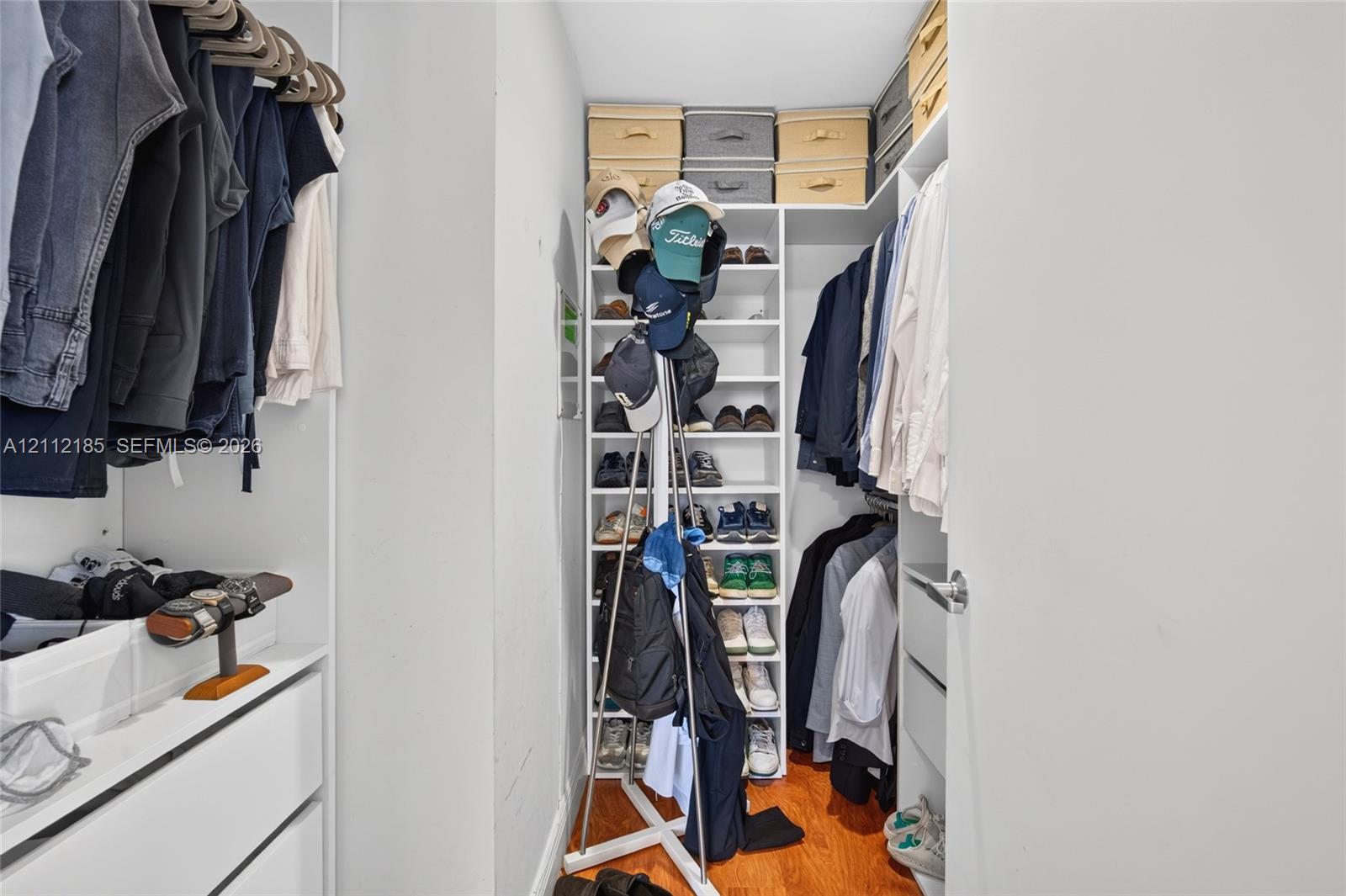 Walk-in closet featuring white built-in shelving, vertical storage compartments, and drawers with polished metal hardware