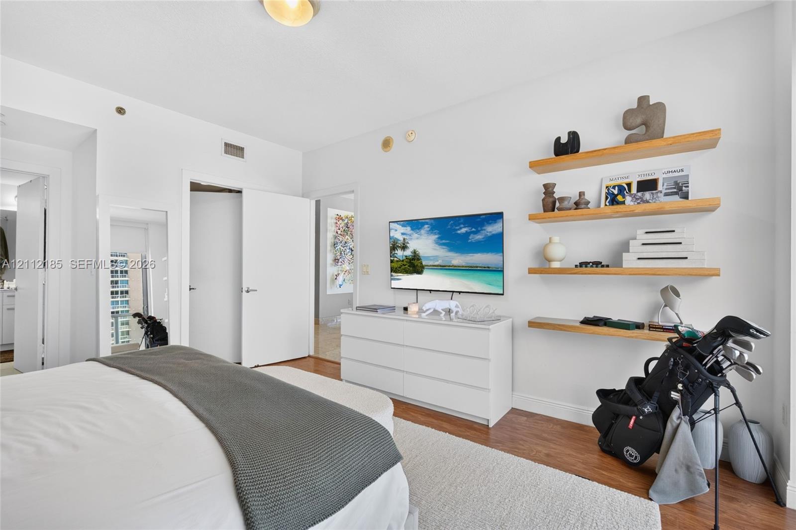 Wood-finish flooring, four floating natural wood shelves, and interior doors with brushed nickel hardware