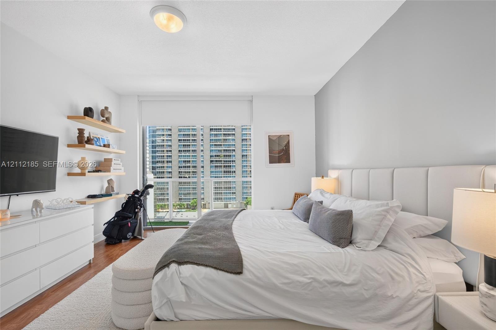Wood-finish flooring, floor-to-ceiling windows with roller shades, and custom built-in floating shelving