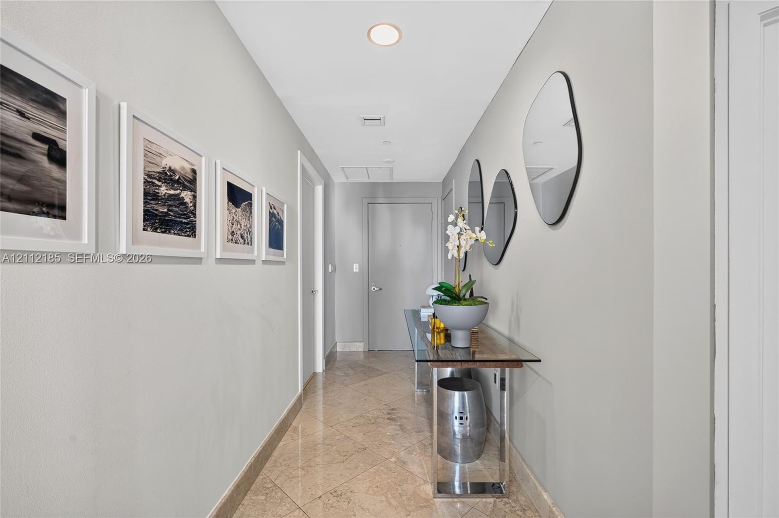 Hallway featuring polished stone-finish tile flooring, recessed ceiling lighting, and solid-core interior doors