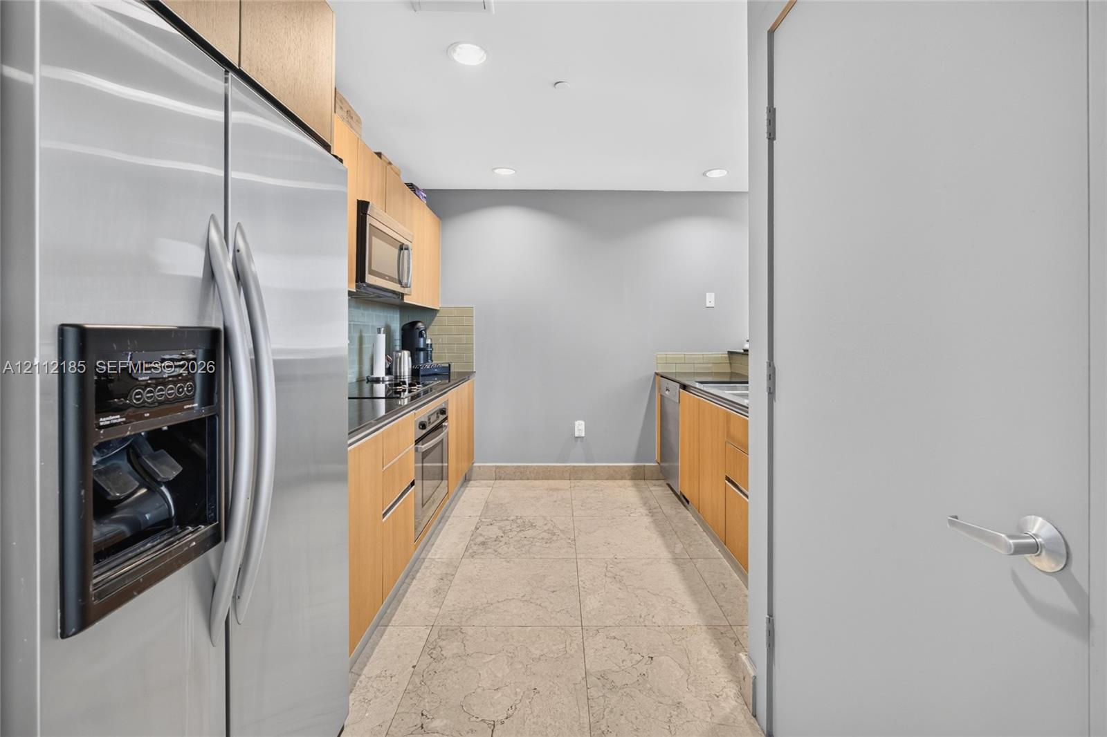 Kitchen featuring flat-panel wood cabinetry, stone flooring, stainless steel side-by-side refrigerator, built-in microwave, and recessed lighting