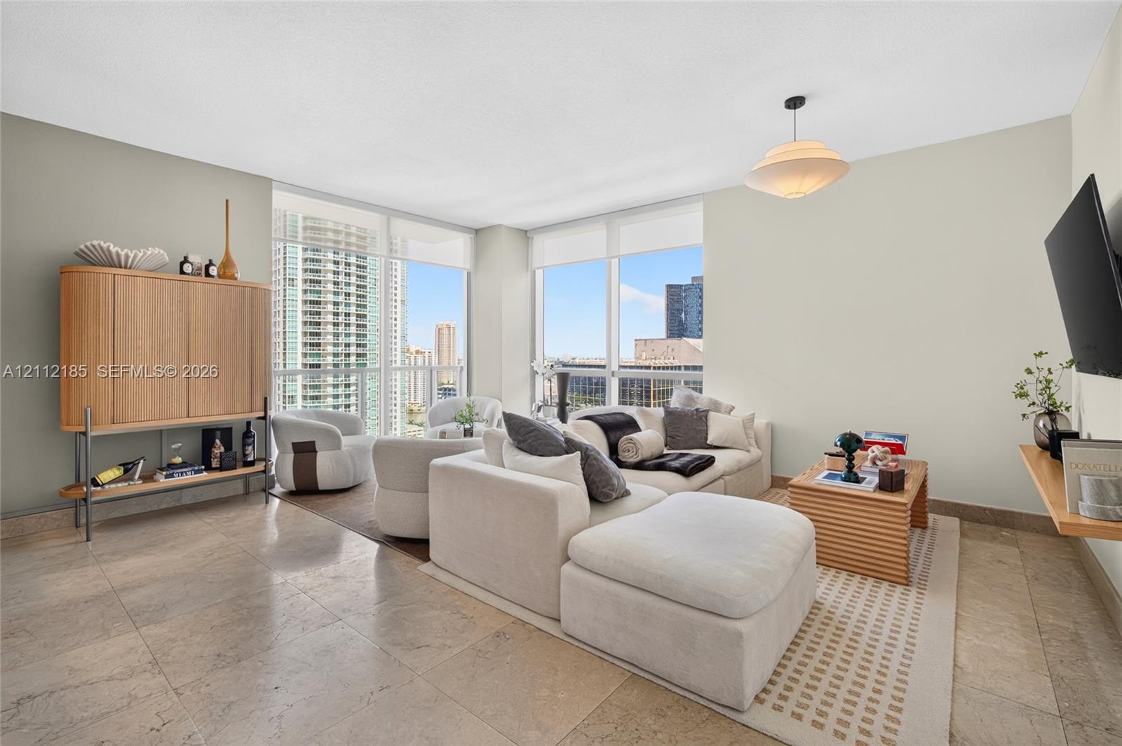 Living area featuring floor-to-ceiling windows, natural stone flooring, and a pendant light fixture