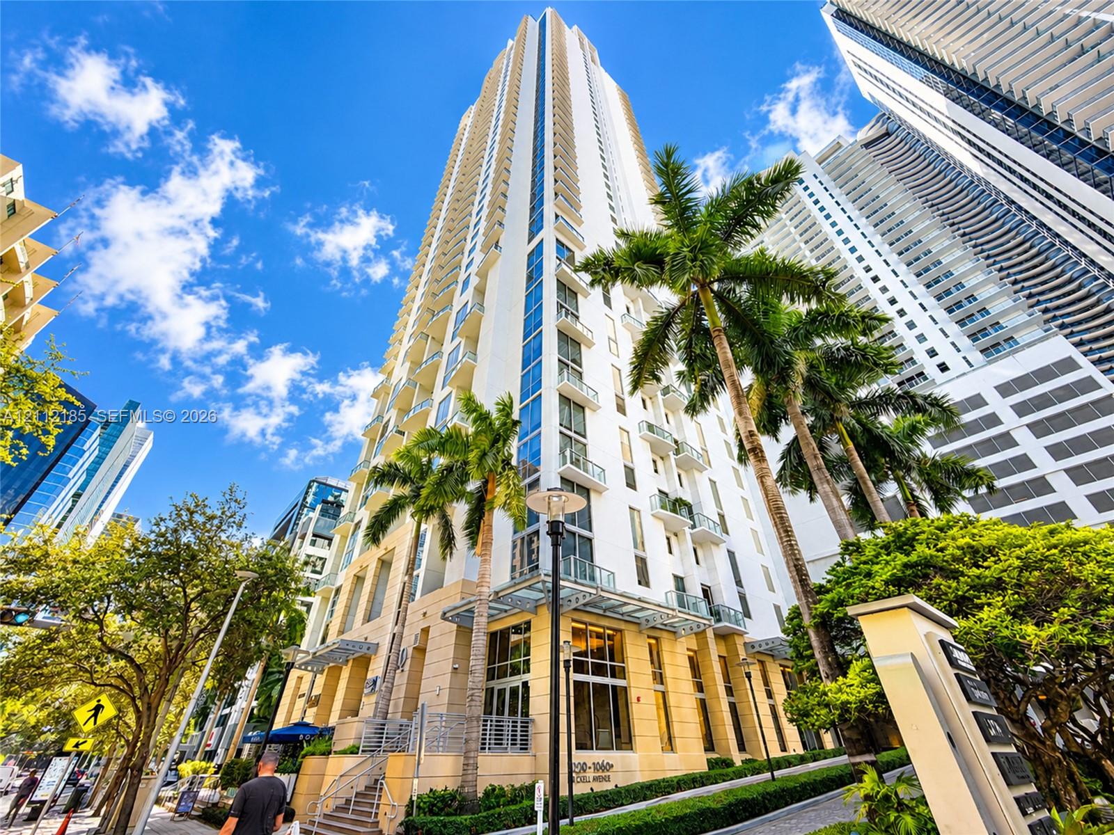 High-rise exterior featuring glass-railed balconies, expansive window arrays, stone-clad facade elements, and tiered architectural detailing