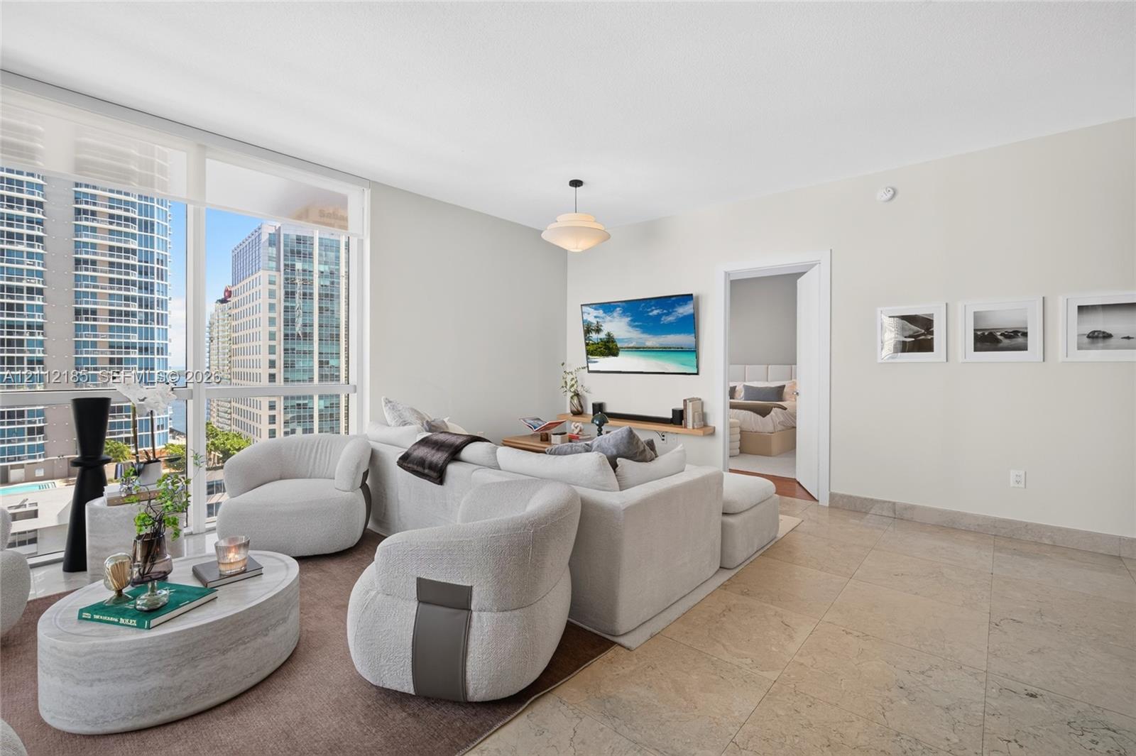 Floor-to-ceiling windows, large-format tile flooring, and a central pendant light fixture