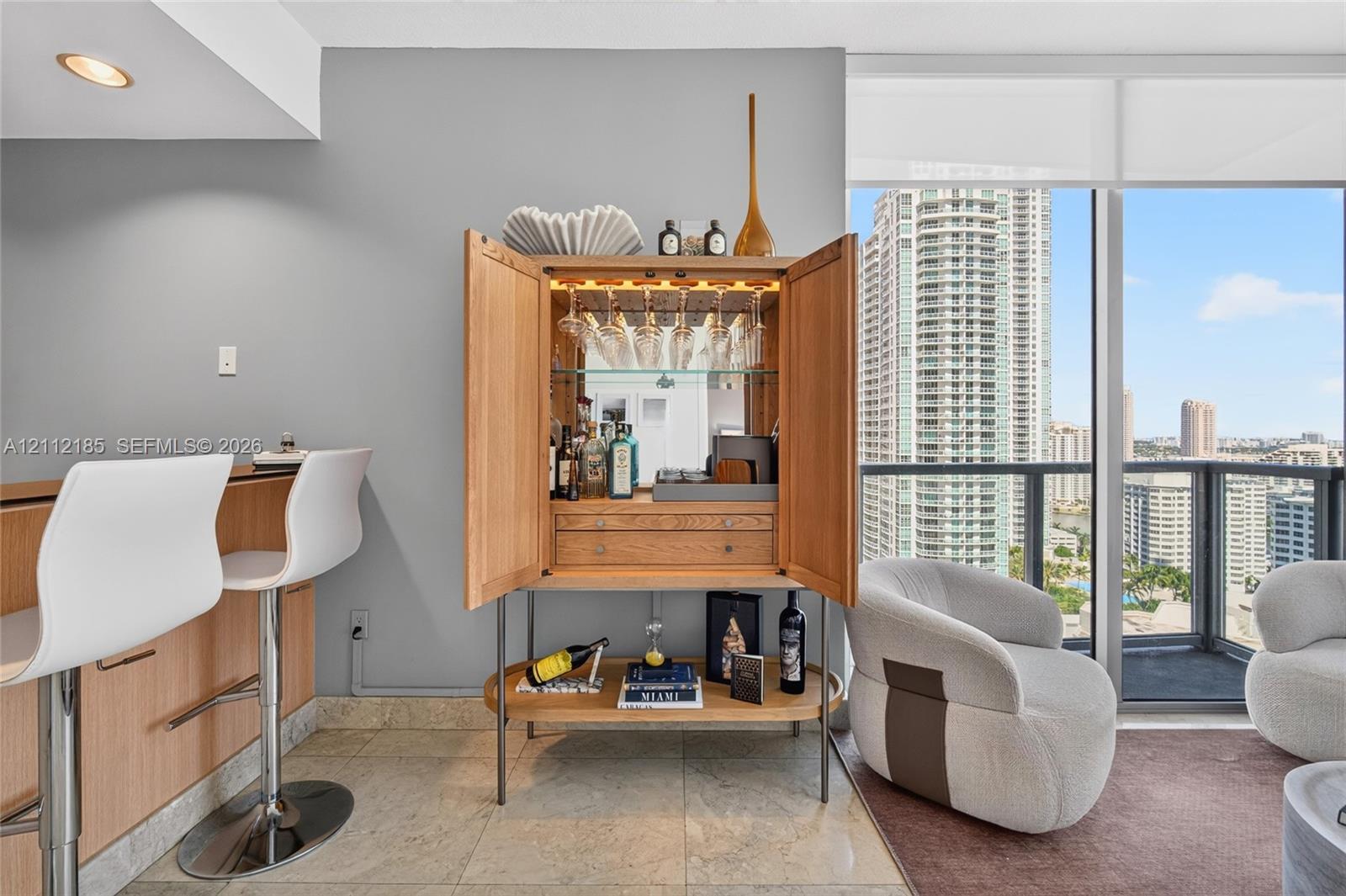 Floor-to-ceiling windows with urban exposure, tile flooring, and integrated wood-finished bar cabinetry featuring mirrored backing and overhead glass storage