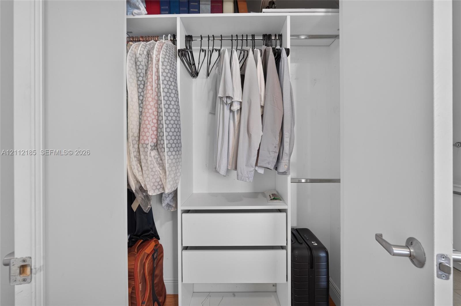 Built-in closet featuring white cabinetry, dual integrated drawers, and metal hanging rods