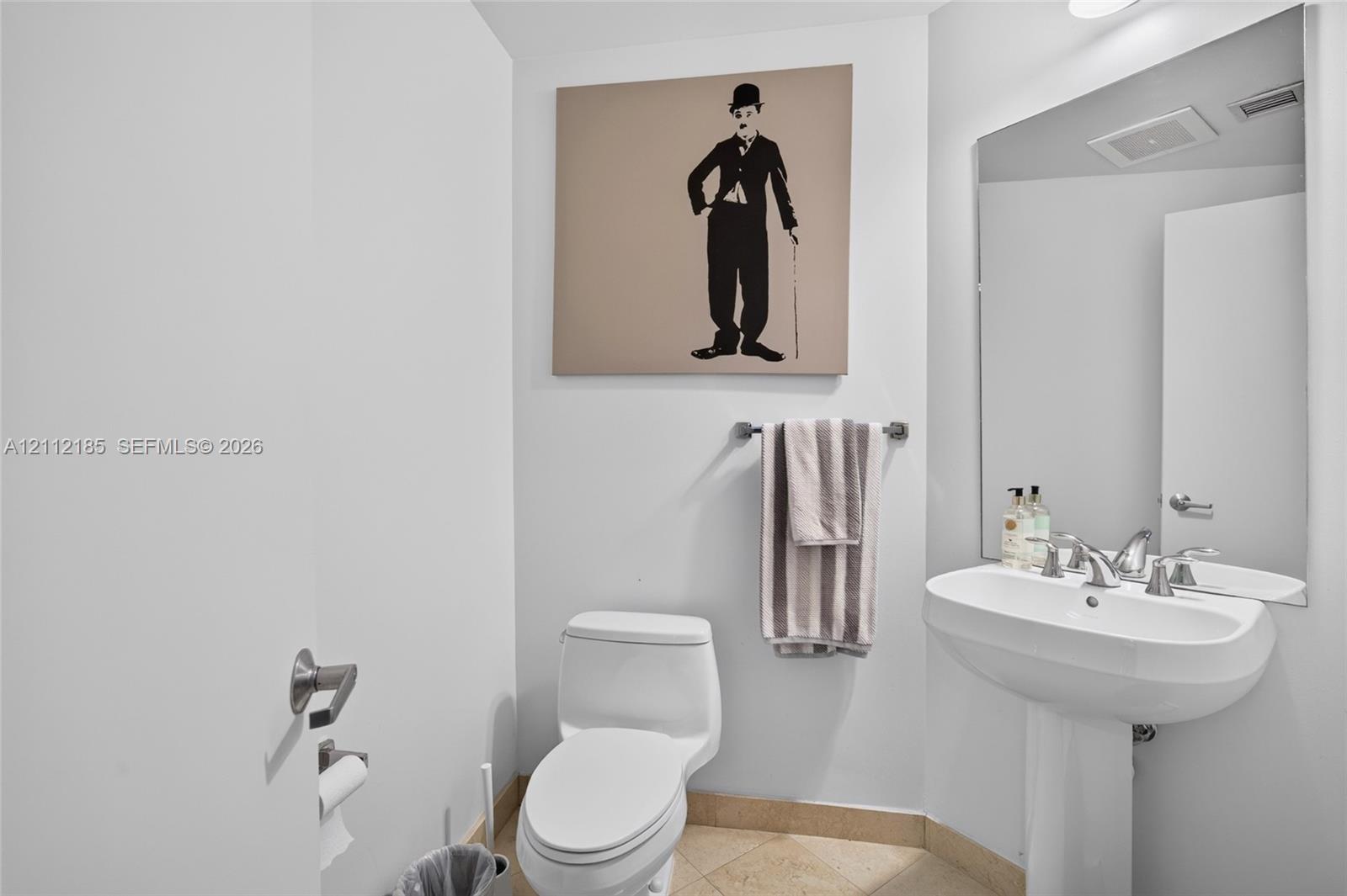 Powder room featuring a pedestal sink, dual-handle chrome faucet, large wall-mounted mirror, and tile flooring