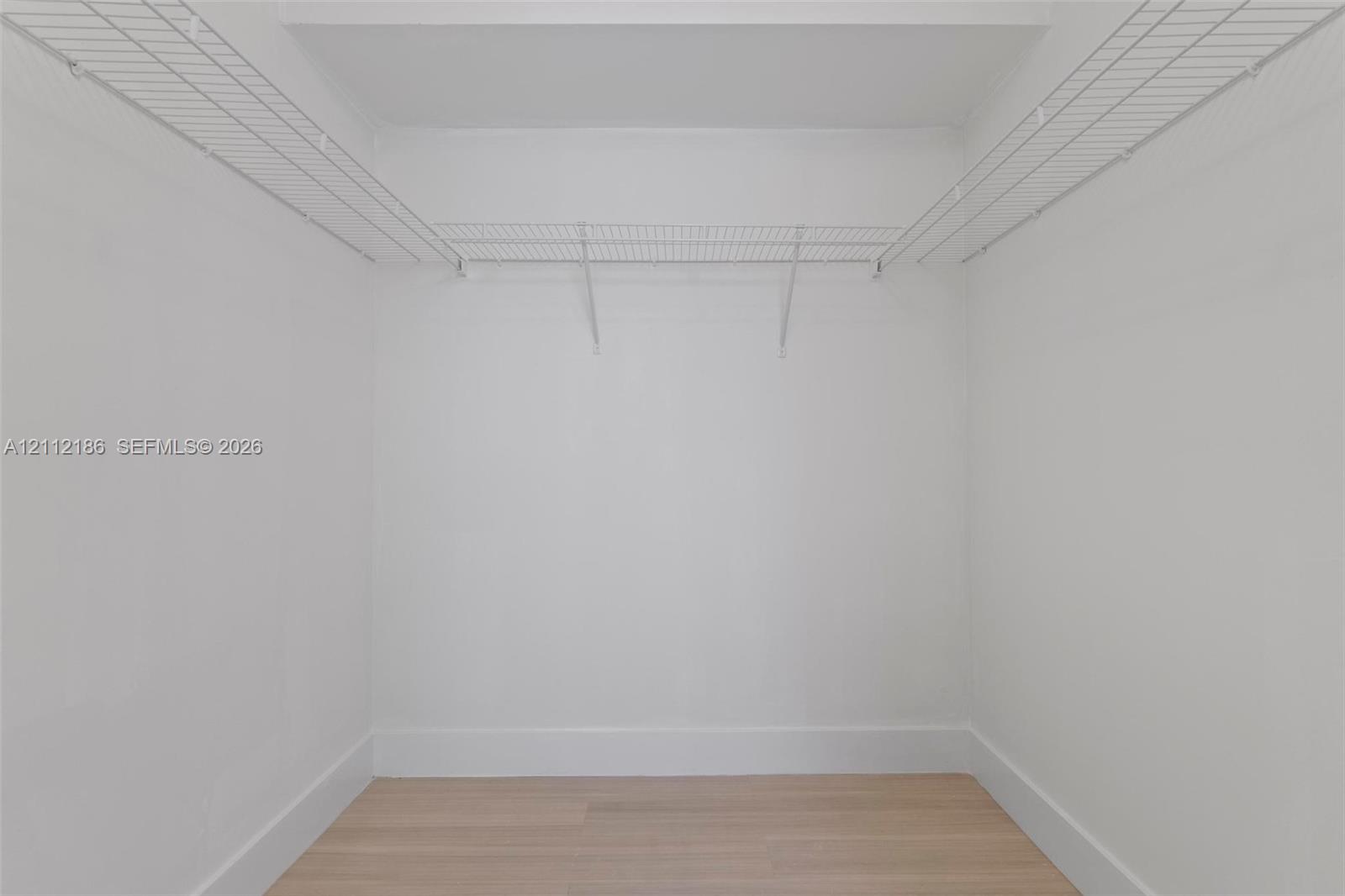 Storage space featuring white walls, wood-finish flooring, and white wire shelving