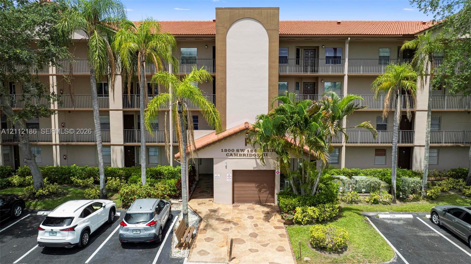 Multi-story residential building featuring a terracotta tile roof, stucco exterior, private covered balconies, and stone-paver walkway