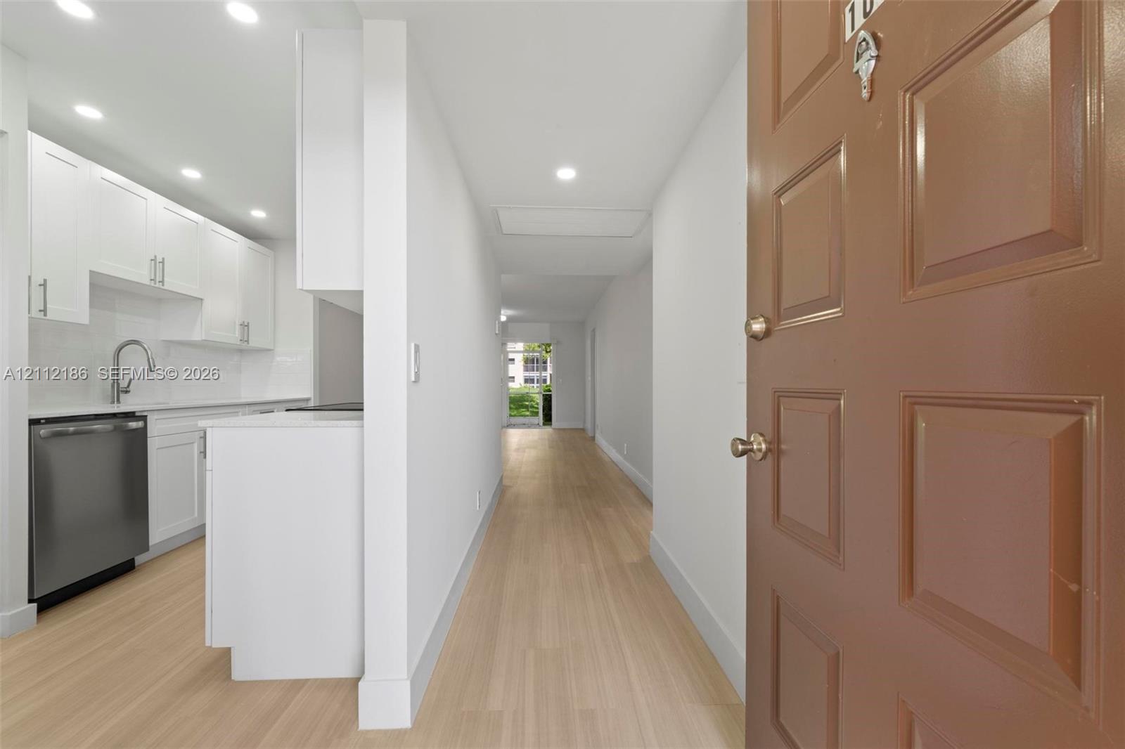 Entryway featuring recessed lighting, wood-finish flooring, white cabinetry, a stainless steel dishwasher, and a gooseneck faucet