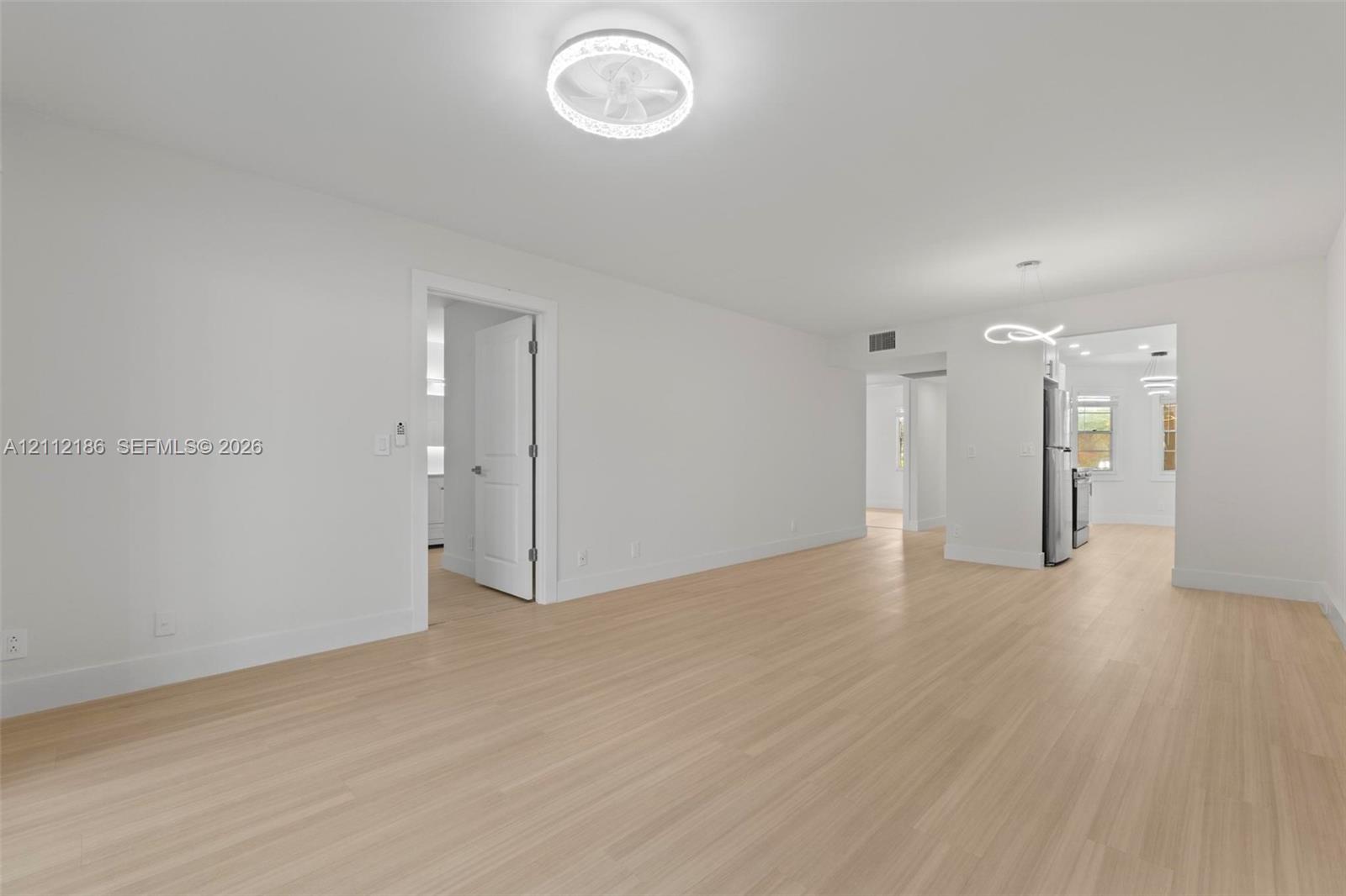 Light-toned wood-finish flooring, recessed lighting, and contemporary circular LED ceiling fixtures