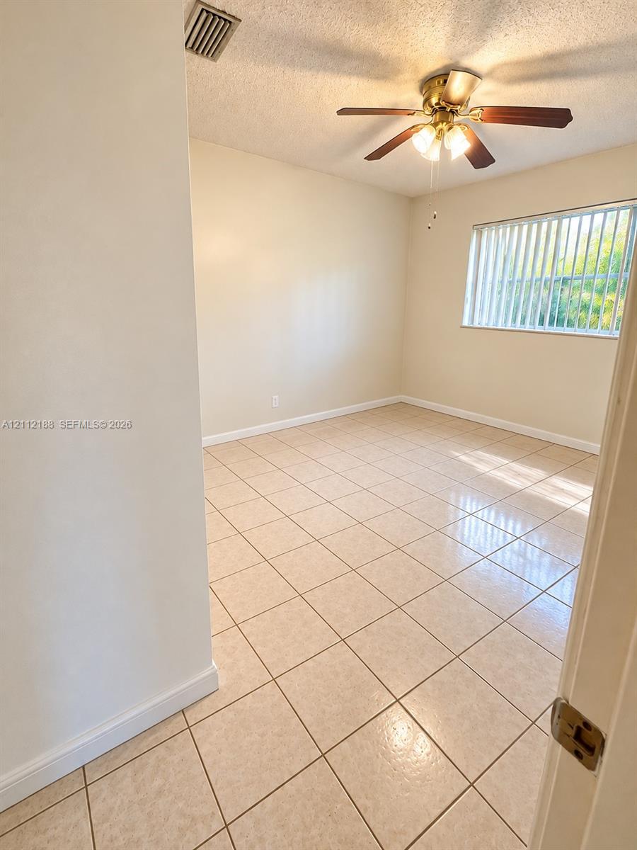 Neutral-toned tile flooring, multi-blade ceiling fan with integrated light fixture, and horizontal window blinds