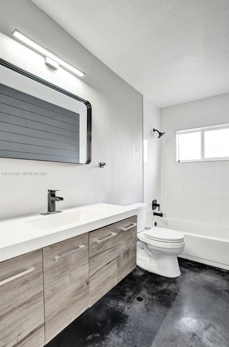 Bathroom featuring a floating wood-finish vanity with an integrated basin, matte black wall-mounted fixtures, rectangular-framed mirror, and tub-shower combination with tiled surround