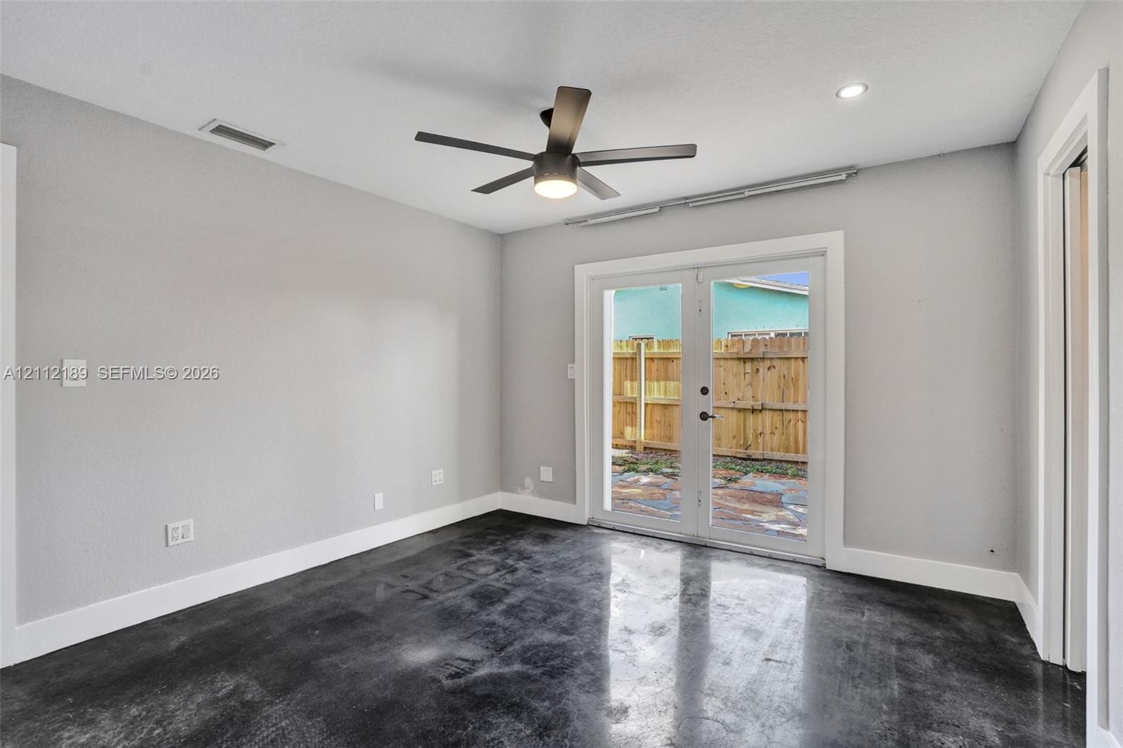 Neutral-toned interior featuring stained concrete flooring, recessed lighting, a modern ceiling fan, and glass French doors