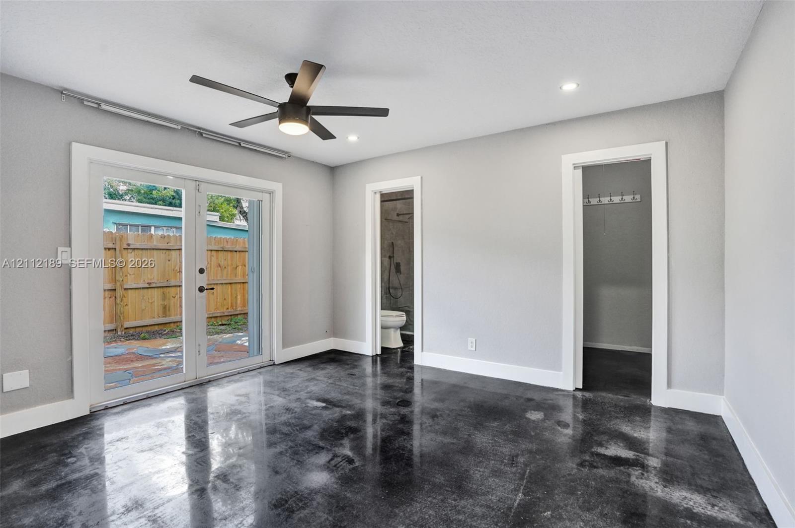 Polished concrete flooring, recessed ceiling lighting, matte black ceiling fan, and double glass-paned doors with exterior access