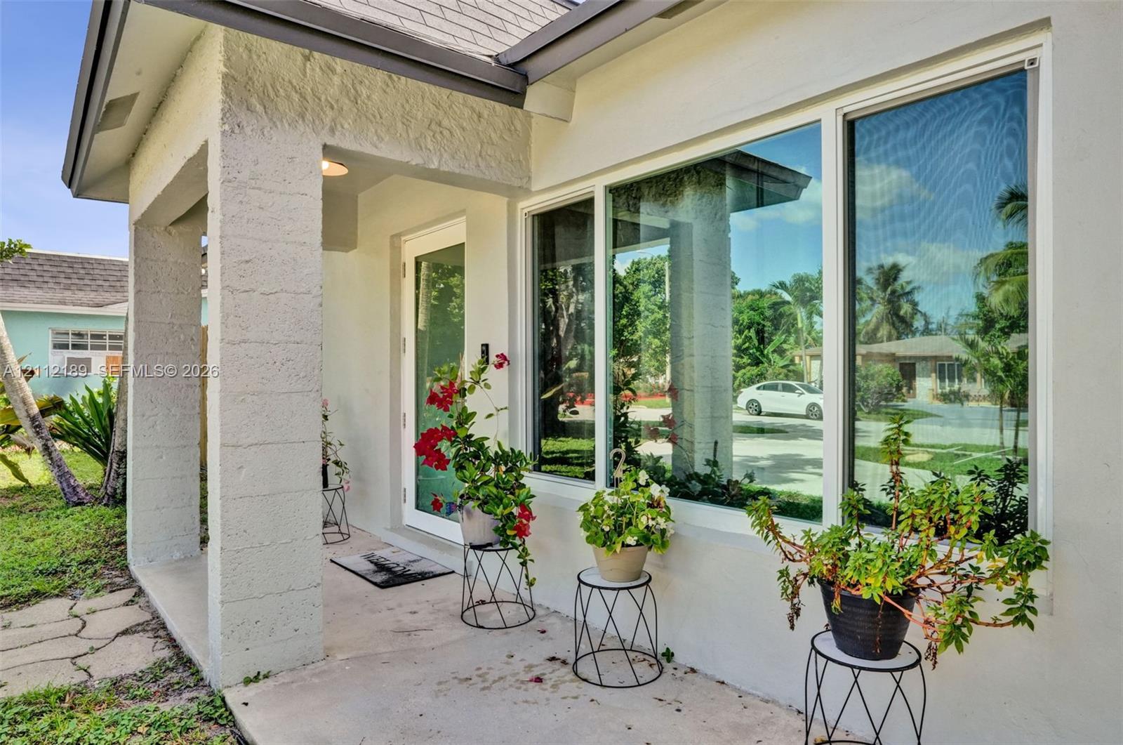 Covered entryway featuring textured masonry columns, oversized picture window, and full-lite glass entry door