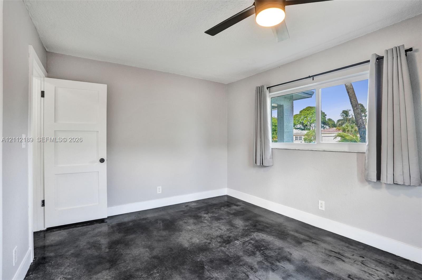 Polished concrete flooring, three-panel interior door, and ceiling fan with integrated lighting