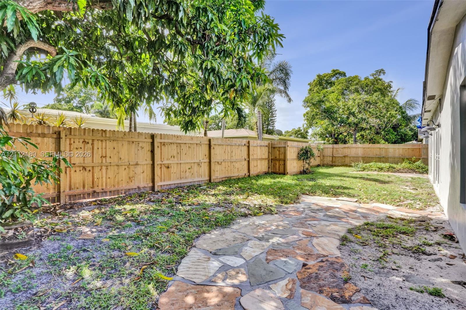 Private backyard featuring a natural stone pathway, wood-style privacy fencing, and mature trees