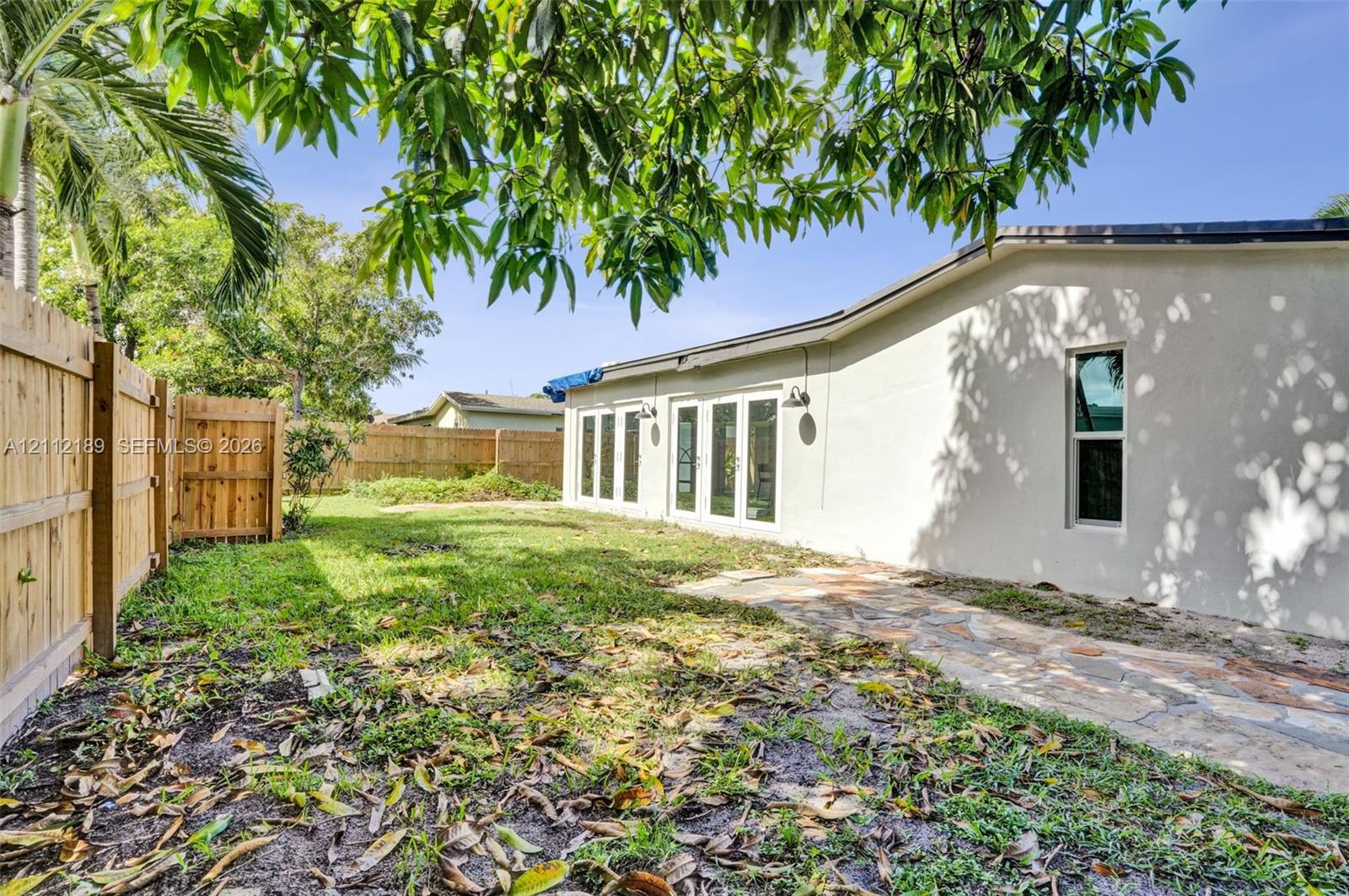 Fenced backyard featuring stone paver hardscaping and multiple sets of exterior glass-paneled doors