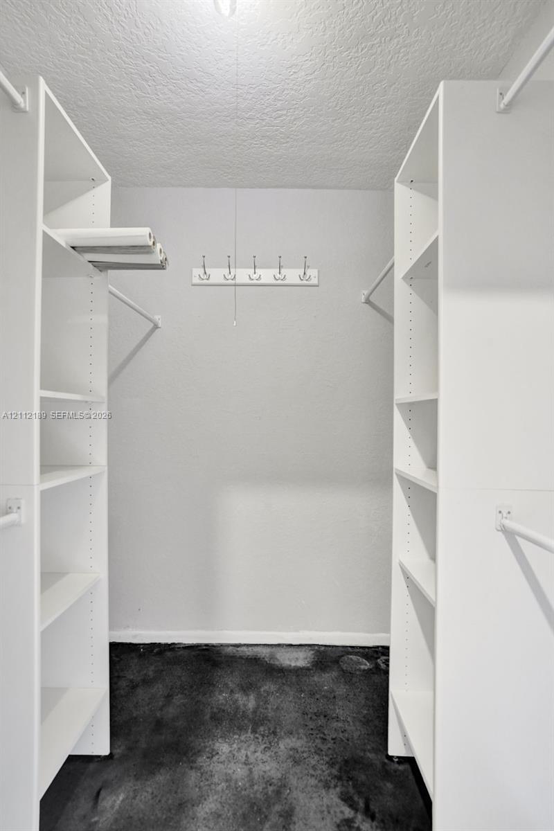 Walk-in closet featuring white built-in shelving, dual hanging rods, and a wall-mounted hook rack