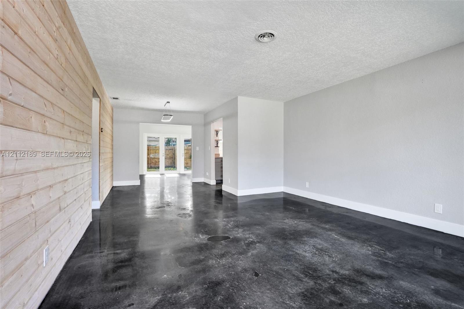 Interior space featuring polished concrete flooring, horizontal wood-plank accent wall, and double glass-paned exterior doors