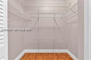 Walk-in closet featuring wood-finish flooring and white coated-wire shelving units