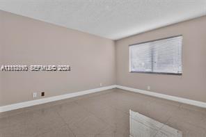 Neutral-toned room featuring tiled flooring, soft-hued walls, and horizontal window blinds
