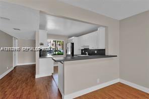 Kitchen featuring white cabinetry, a dark countertop, a stainless steel refrigerator, and wood-finish flooring
