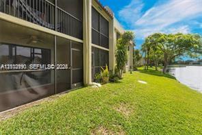 Multi-level exterior featuring screened balconies with metal railings, waterfront grounds, and mature trees
