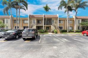 Two-story exterior featuring tan stucco siding, a tiled roof, screened balconies, and mature palm trees Two-story exterior featuring tan stucco siding, a tiled roof, screened balconies, and mature palm trees