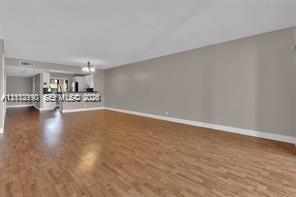 Open-concept interior featuring wood-finish flooring, neutral wall tones, and a breakfast bar Open-concept interior featuring wood-finish flooring, neutral wall tones, and a breakfast bar