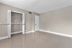 Neutral-toned interior room featuring polished stone-finish flooring, a built-in closet with folding doors, and a solid-core interior door