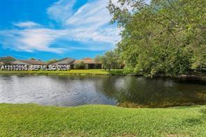 Waterfront property featuring a manicured lawn, mature trees, and shingled roofing