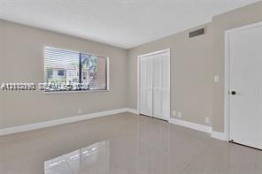Neutral-toned interior featuring large-format tile flooring, a horizontal sliding window, and a dual-panel closet door