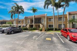 Two-story exterior featuring a clay tile roof, screened-in balconies, stucco siding, and mature palm trees