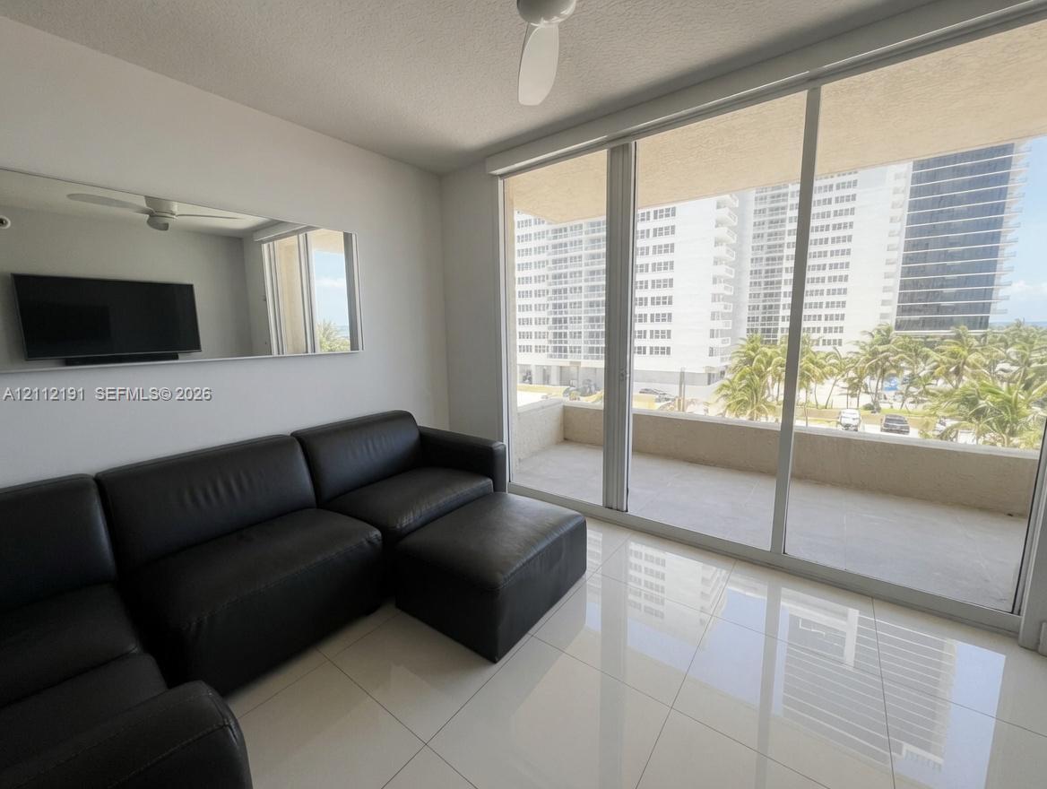 Floor-to-ceiling glass sliding doors, private balcony, polished tile flooring, built-in wall mirror, and ceiling fan Floor-to-ceiling glass sliding doors, private balcony, polished tile flooring, built-in wall mirror, and ceiling fan