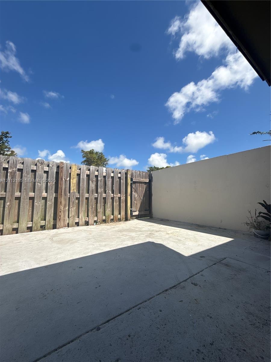 Private patio featuring concrete flooring, a wooden privacy fence, and an integrated gate