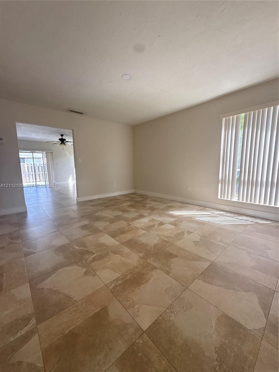 Large-format tile flooring, neutral wall paint, and vertical window blinds