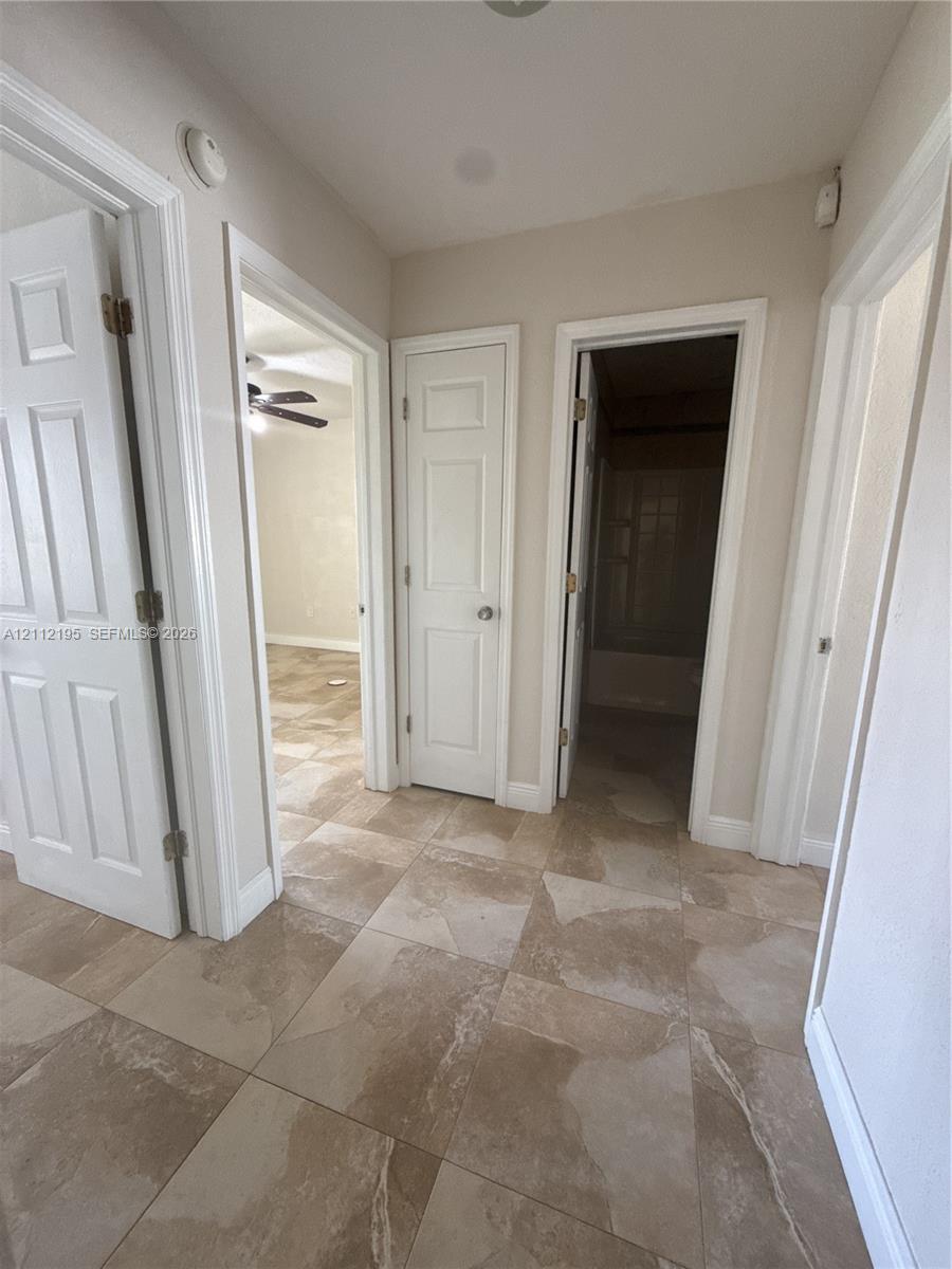 Hallway featuring large-format ceramic tile flooring, neutral wall paint, and traditional six-panel interior doors
